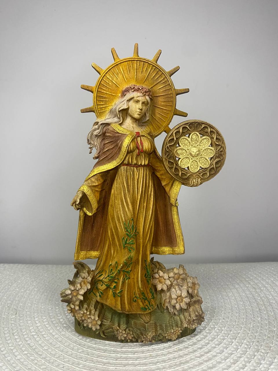 Decorative statue of a woman with a sun emblem on a textured surface