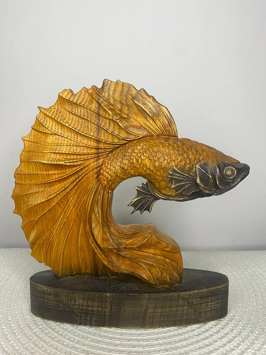 Wooden sculpture of a gold fish on a white background