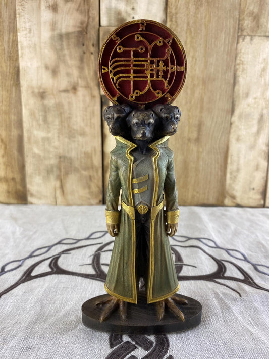Statue of a three-headed dog-like creature wearing a coat, with a circular symbol behind it