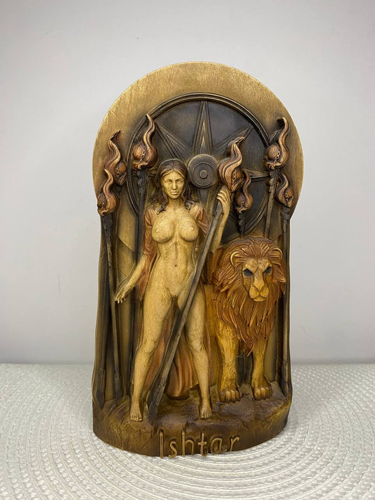 A carved wooden Ishtar figurine featuring a nude goddess holding a sword, standing beside a lion, set against a circular star motif. The name 'Ishtar' is carved at the base.