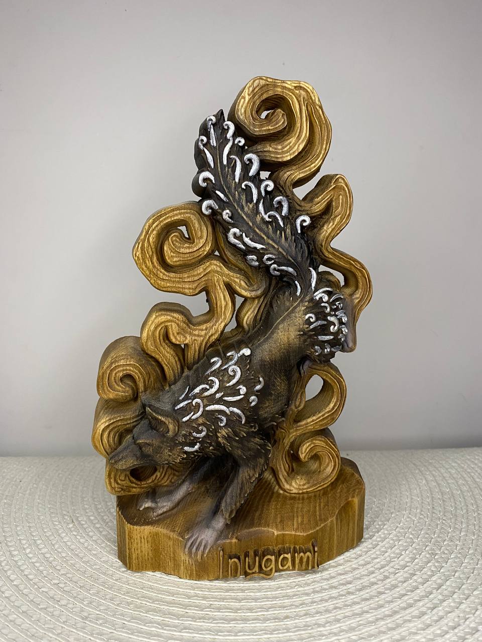 Handcrafted wooden Inugami statue inspired by Japanese folklore, featuring the mystical dog spirit surrounded by flowing wind motifs and ornate carved details, hand-painted in natural wood, gold, silver, and black tones. Japanese mythology altar decor and collectible sculpture.