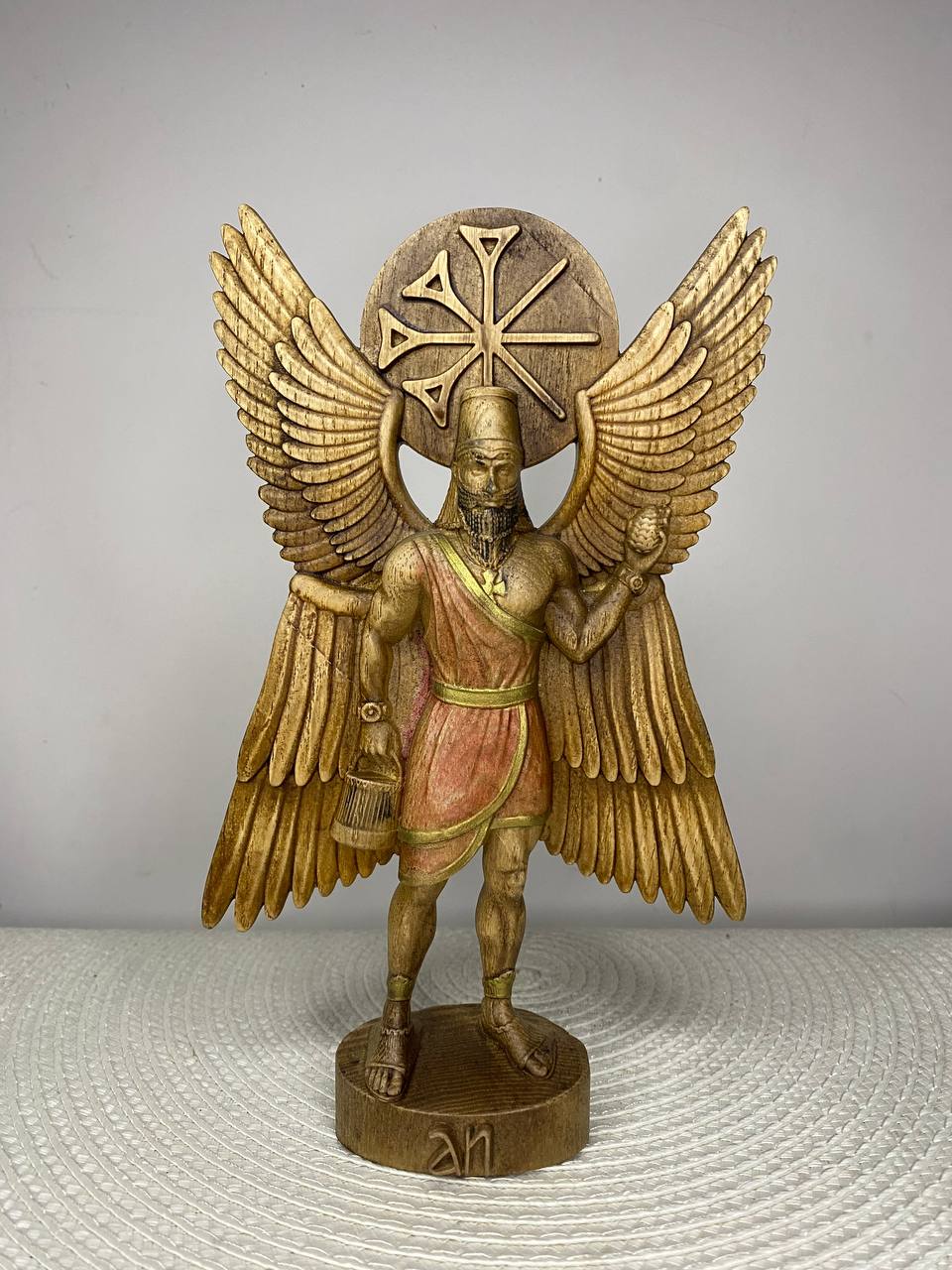Handcrafted wooden Anu statue inspired by the Mesopotamian sky god, featuring majestic wings, the Star of Anu symbol, and ceremonial attire, holding a sacred vessel and pine cone, hand-carved from natural wood and finished in rich golden and bronze tones. Mesopotamian mythology altar decor and collectible sculpture.
