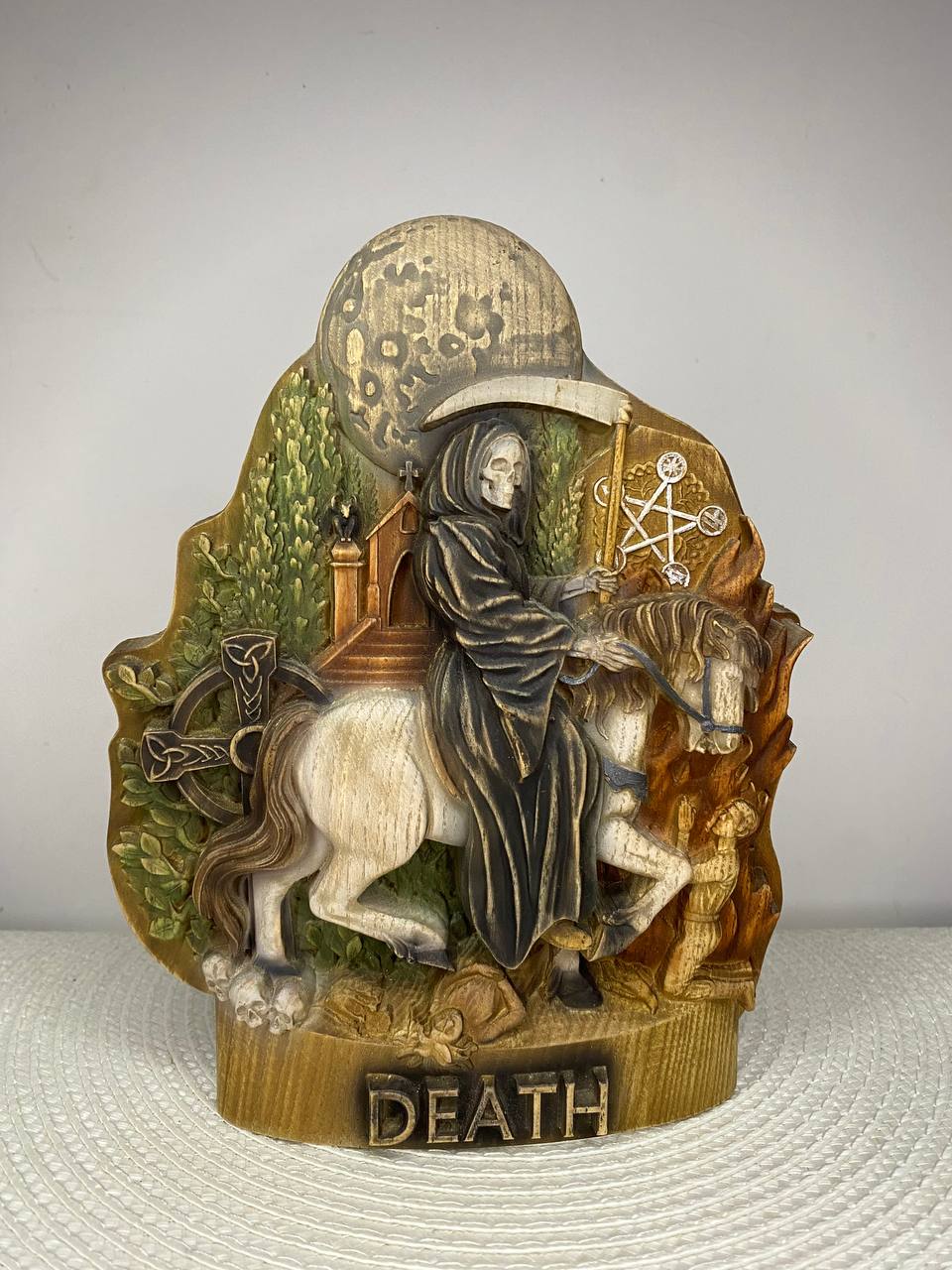 Hand-painted wooden statue of Death riding a white horse beneath a full moon, holding a scythe and surrounded by symbolic elements, inspired by gothic folklore, mortality, transformation, and dark fantasy decor.
