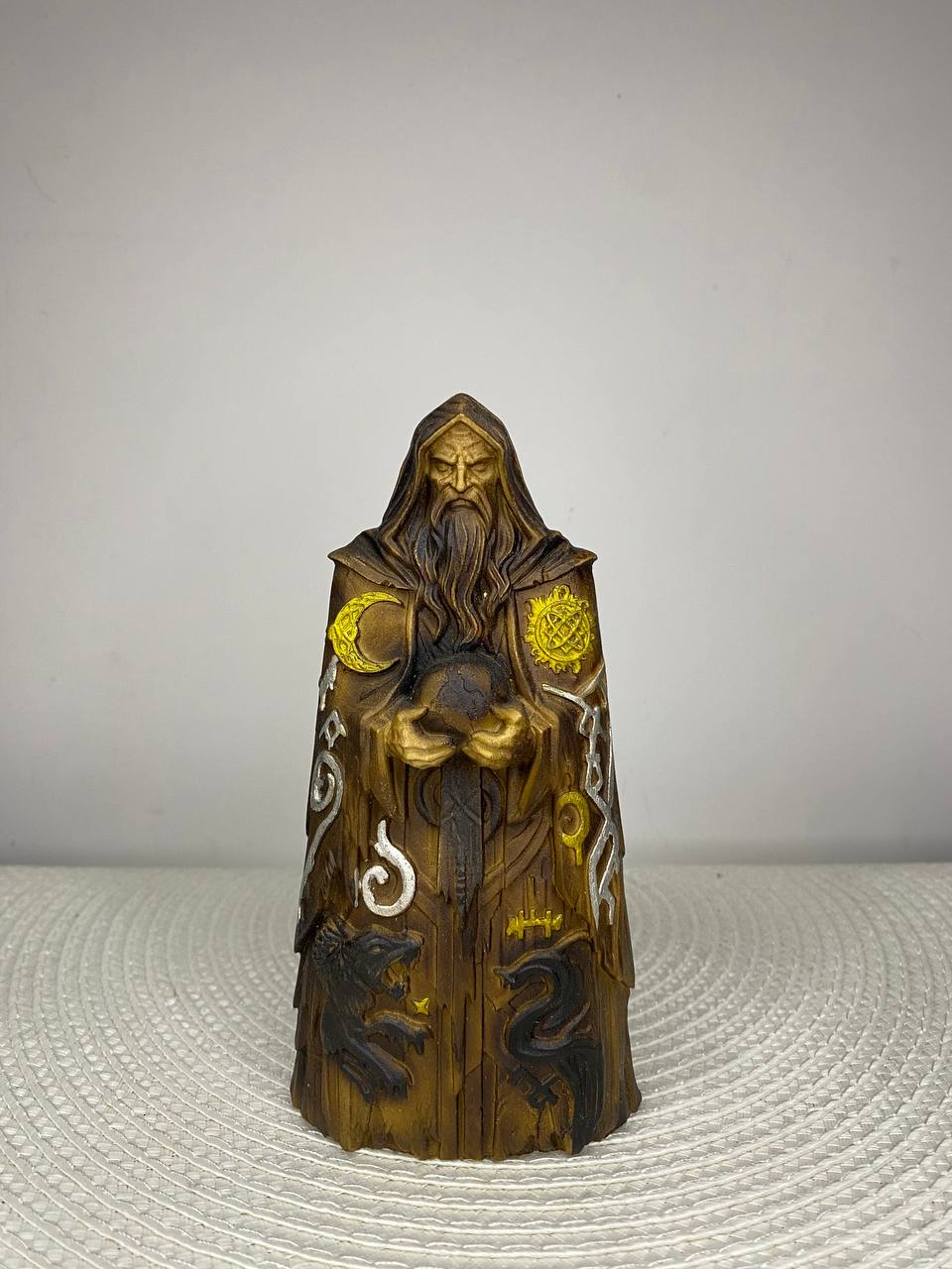 Handcrafted wooden Chernobog statue inspired by Slavic mythology, depicting the Dark God in a hooded robe holding a mystical sphere, adorned with sun and moon symbols, ancient runes, and sacred animal motifs, hand-painted in natural wood, gold, bronze, black, and silver tones. Slavic pagan altar decor and collectible sculpture.