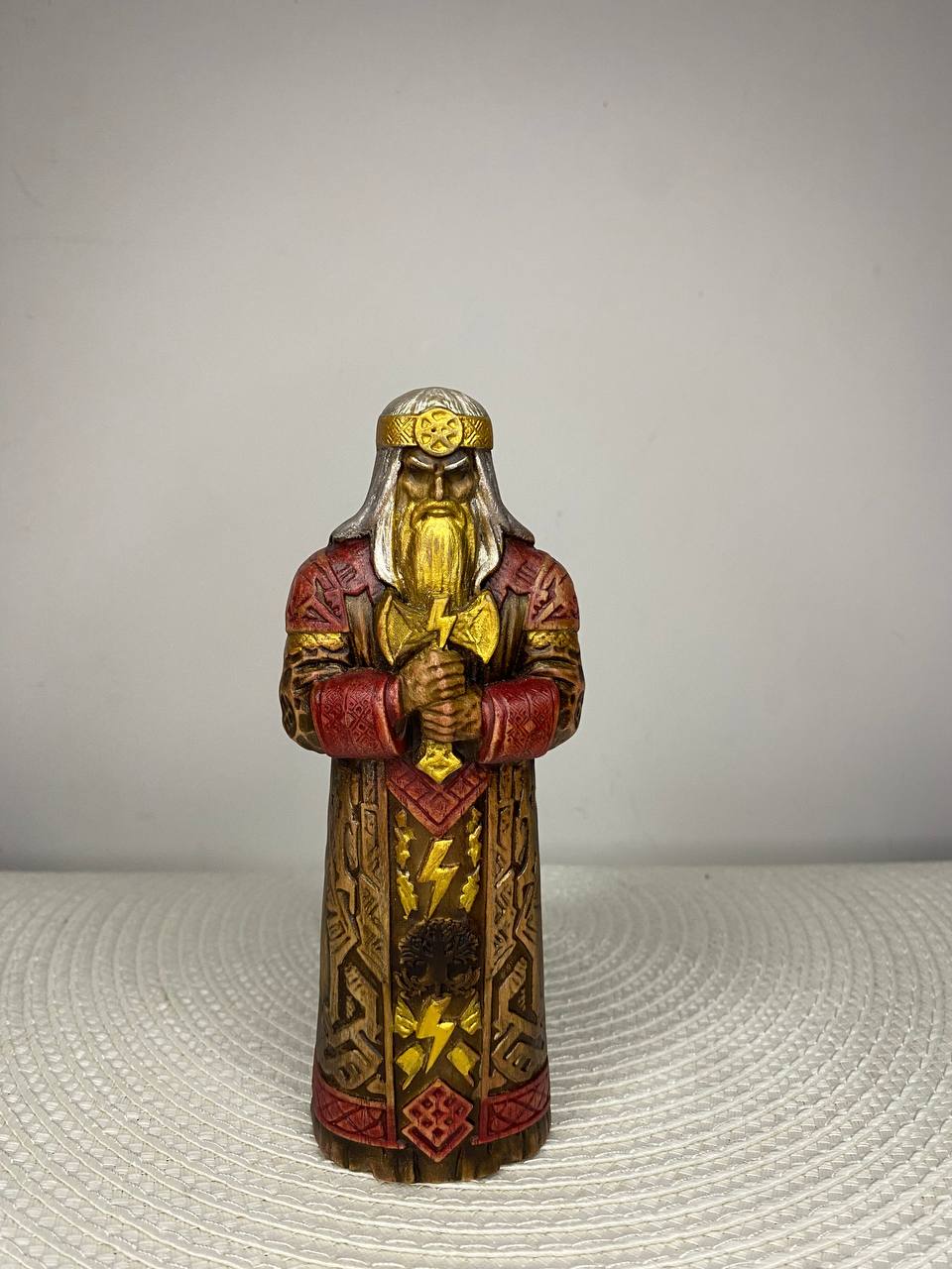 Handcrafted wooden Perun statue inspired by Slavic mythology, depicting the Slavic god of thunder holding a ceremonial axe, adorned with sacred runes, lightning symbols, and the Tree of Life, hand-painted in natural wood, gold, bronze, red, and silver tones. Slavic pagan altar decor and collectible sculpture.