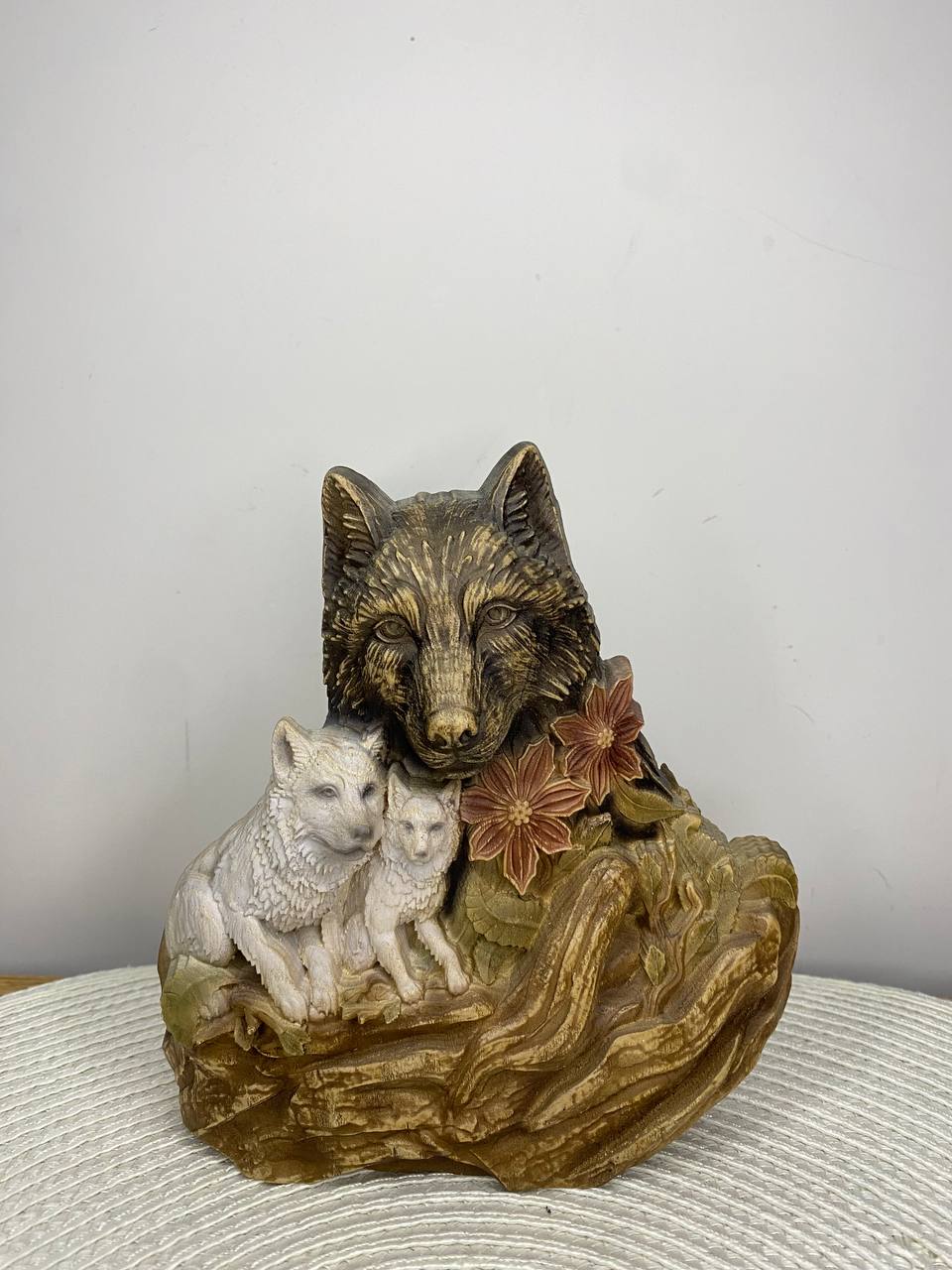 Handcrafted wooden wolf family statue featuring a protective mother wolf with two wolf pups, detailed flowers and woodland elements, hand-painted in natural wood, gold, white, and earthy tones. Rustic wildlife decor and meaningful family gift.