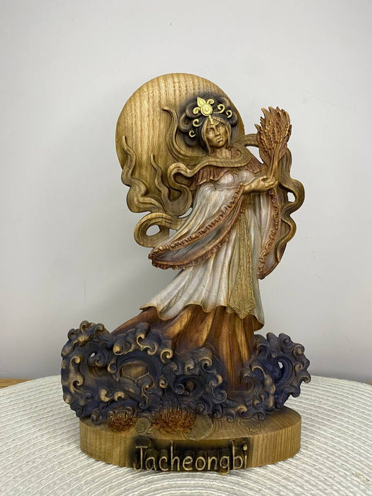Hand-painted wooden statue of Jacheongbi, Korean goddess of harvest and abundance, holding grain sheaf and standing among waves, inspired by Korean mythology and sacred feminine symbolism.
