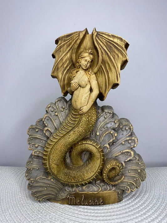 Handcrafted wooden Melusine statue inspired by European folklore, depicting the legendary winged serpent goddess with a coiled dragon tail rising from ocean waves, hand-painted in natural wood, gold, bronze, and gray tones. Fantasy mythology altar decor and collectible sculpture.