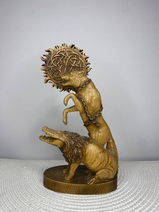 Handcrafted wooden Fenrir statue inspired by Norse mythology, featuring the legendary giant wolf bound by magical chains with a Celtic knot sun behind and a snarling wolf at its feet, hand-painted in natural wood, gold, and bronze tones. Viking altar decor and mythology collectible.