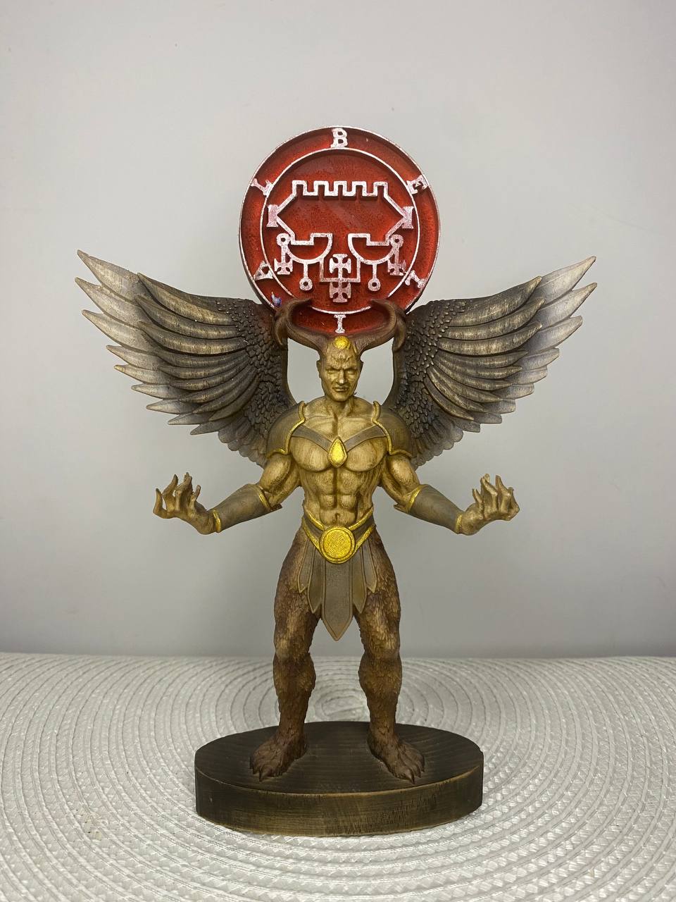 Handcrafted wooden Belial statue inspired by the Ars Goetia demon, featuring powerful wings, ram horns, a glowing sigil, and muscular humanoid form, hand-painted in natural wood, gold, and bronze tones. Occult altar decor and demonology collectible.